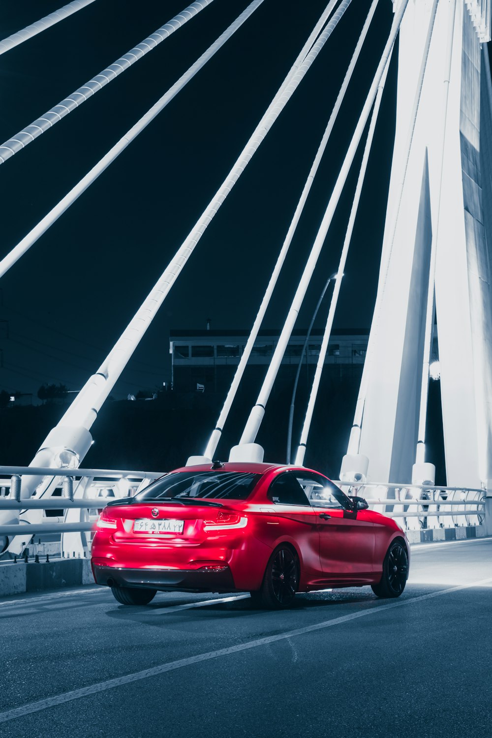 a red car driving across a bridge at night