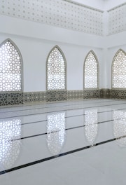 Glass storefront with Islamic design elements in a commercial area.