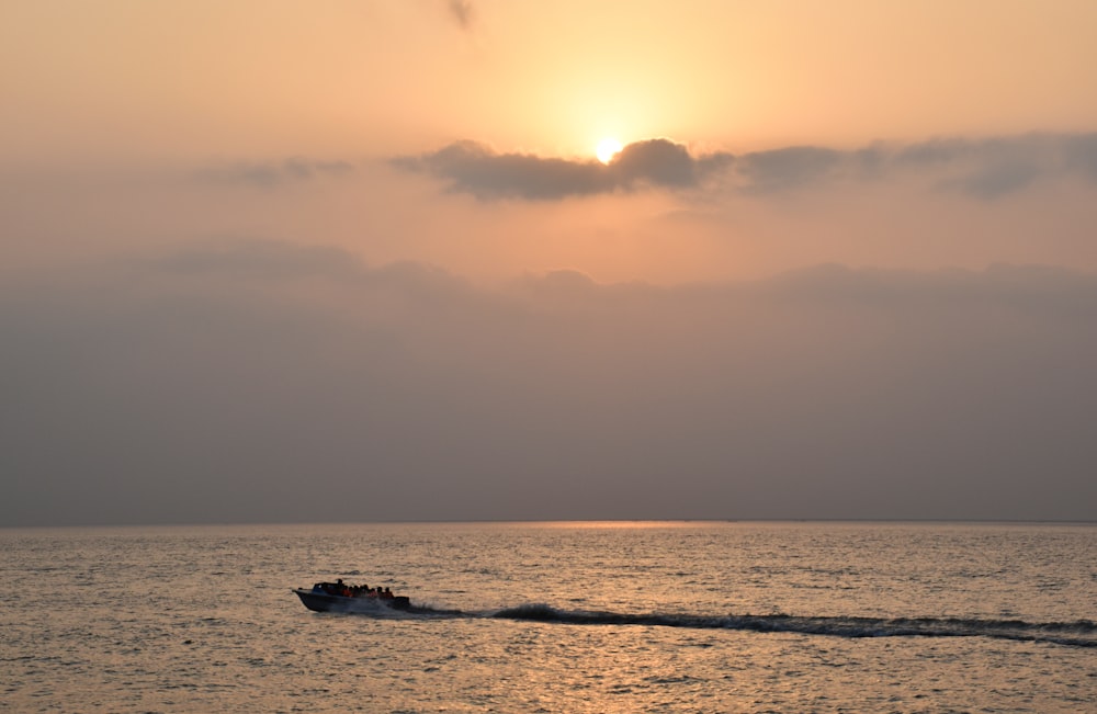 a boat traveling across a body of water under a cloudy sky