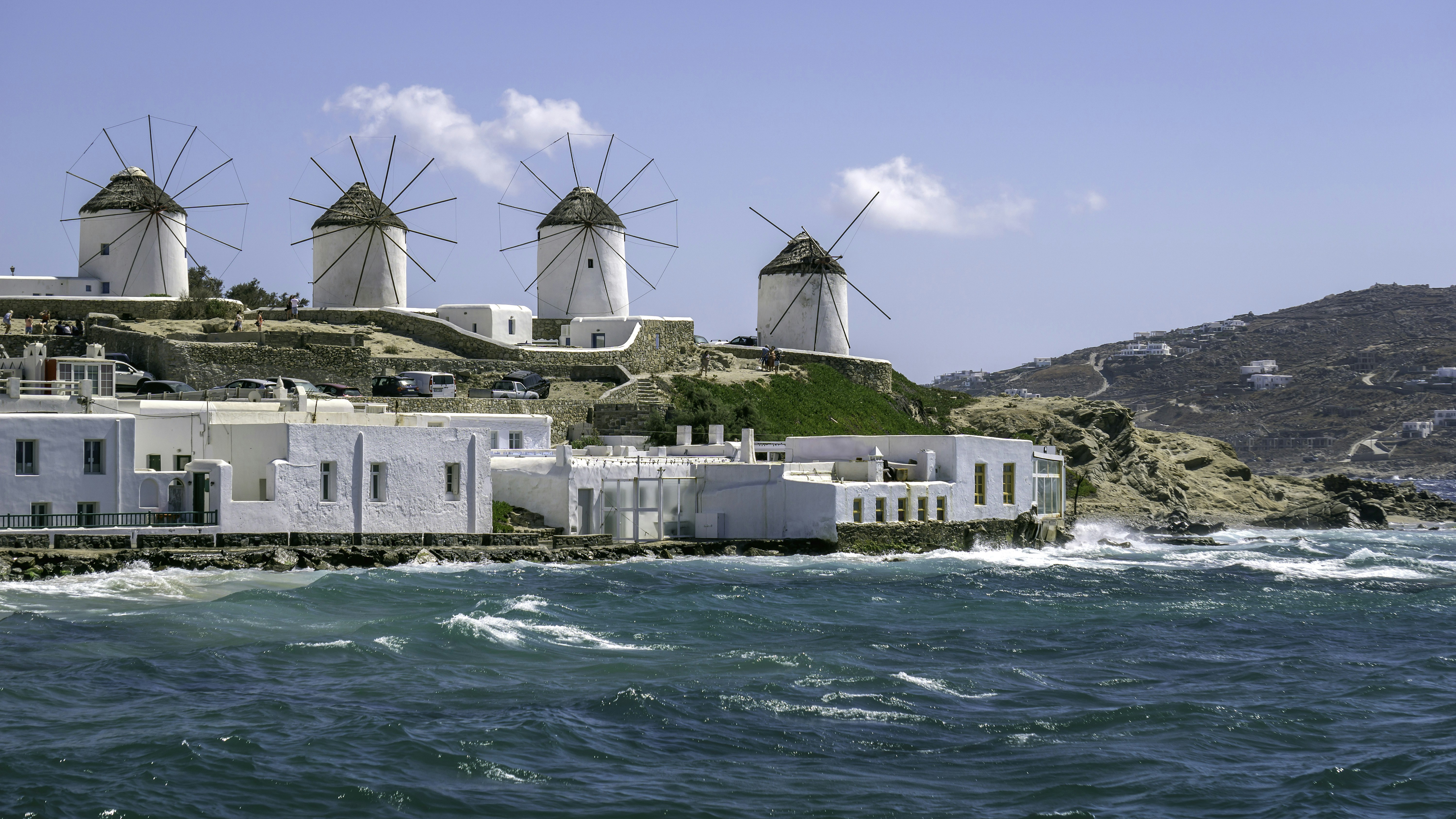 a row of windmills sitting on top of a hill next to the ocean