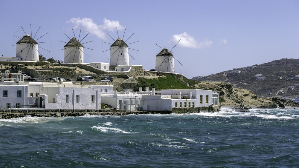 a row of windmills sitting on top of a hill next to the ocean