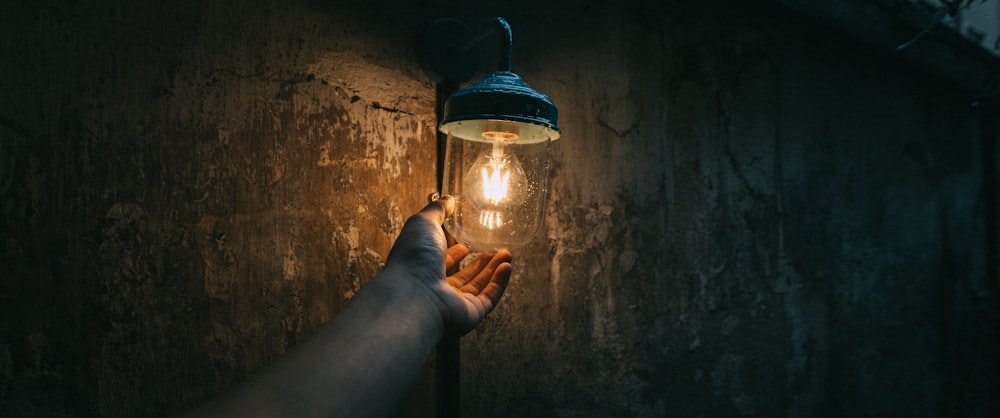 una persona che tiene una lampadina su un muro