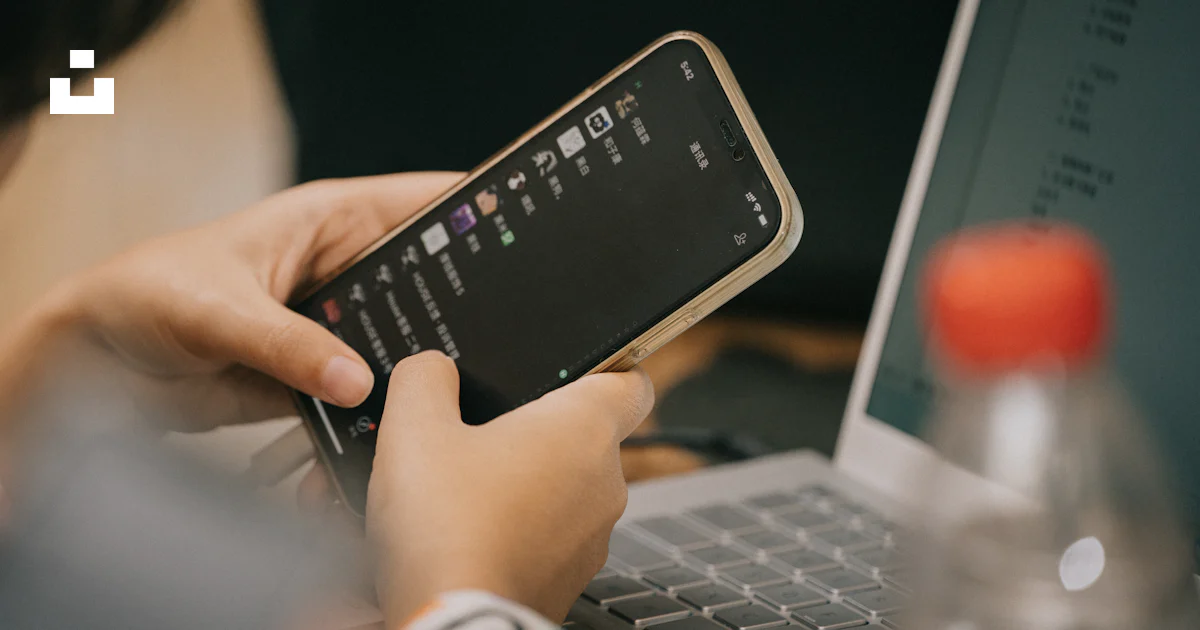 A Person Using A Cell Phone While Sitting In Front Of A Laptop Photo a-person-using-a-cell-phone-while-sitting-in-front-of-a-laptop-photo