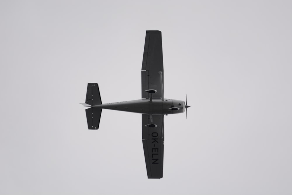 a small airplane flying through a gray sky