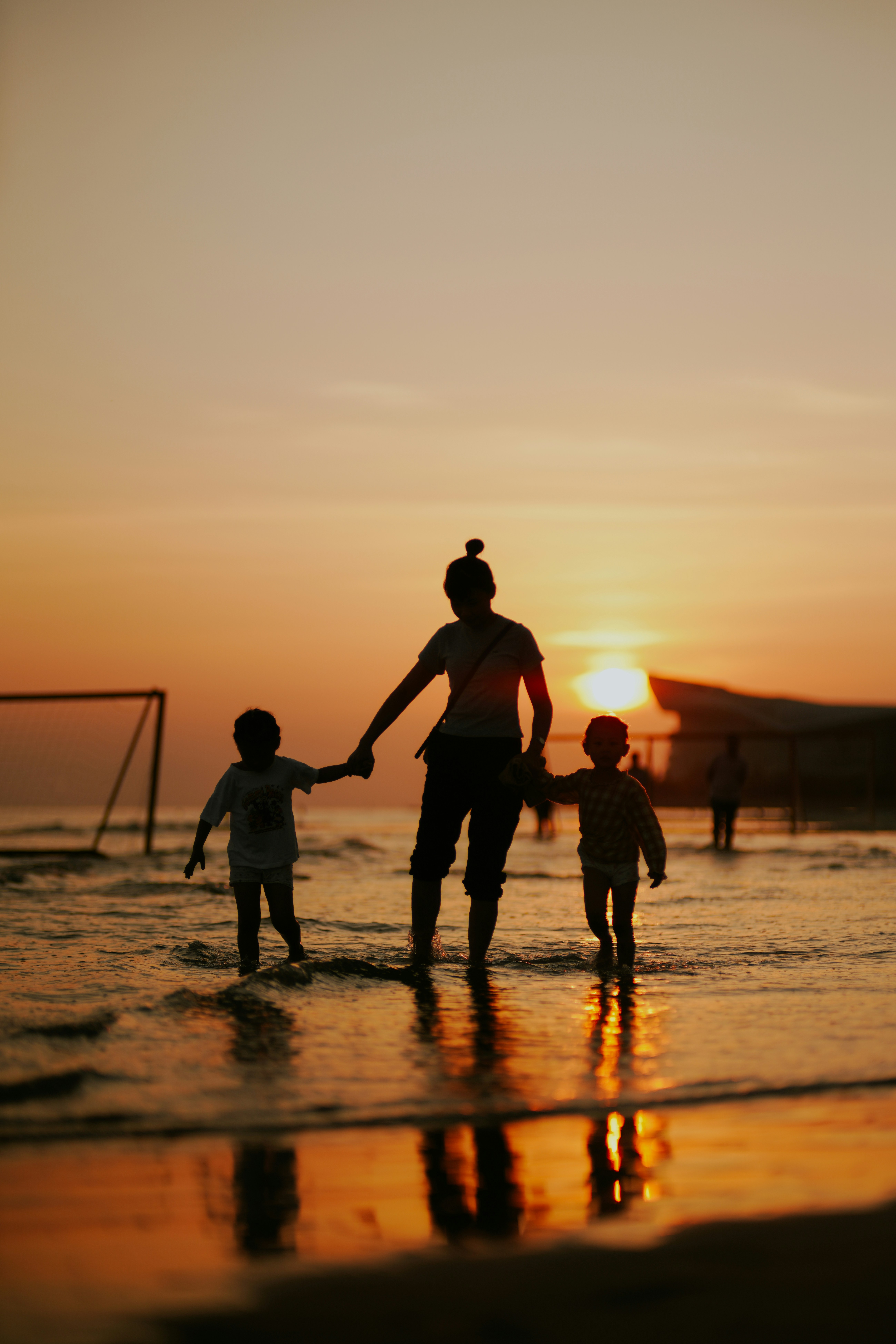 a woman holding hands with two children on the beach
