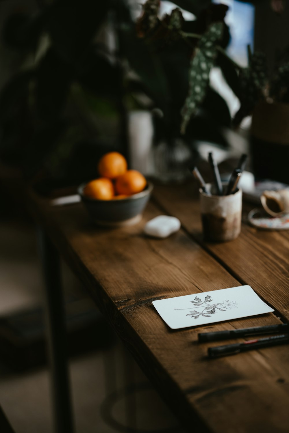 a wooden table topped with a bowl of oranges