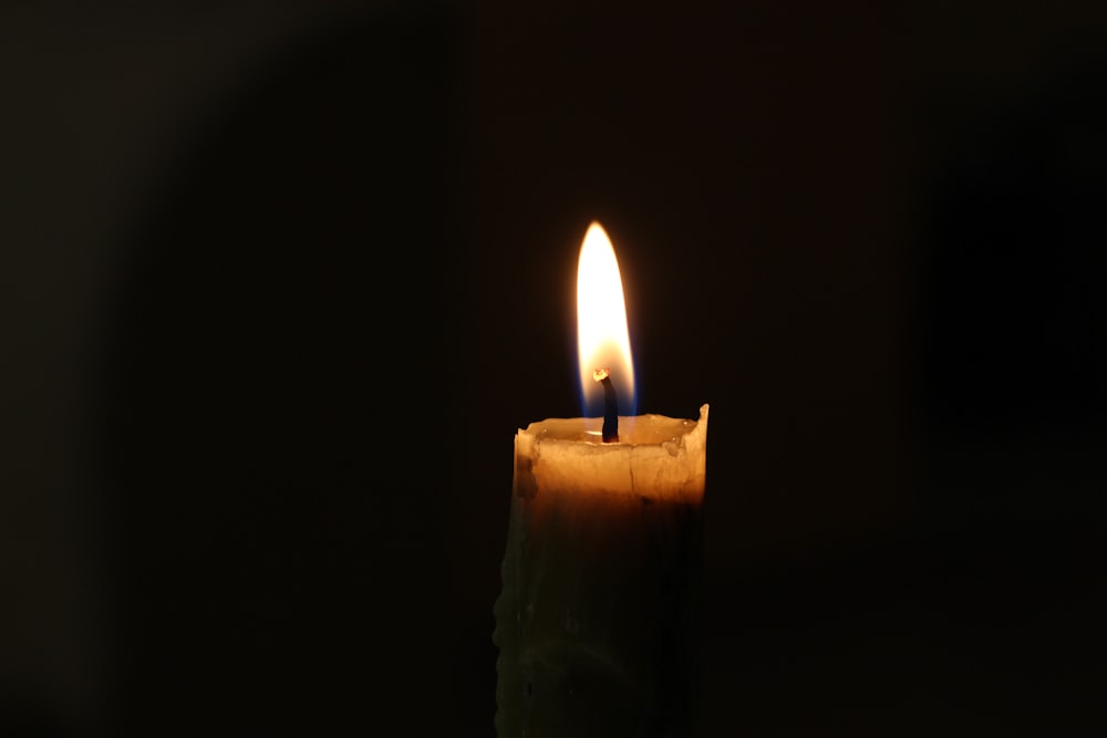 a lit candle with a dark background