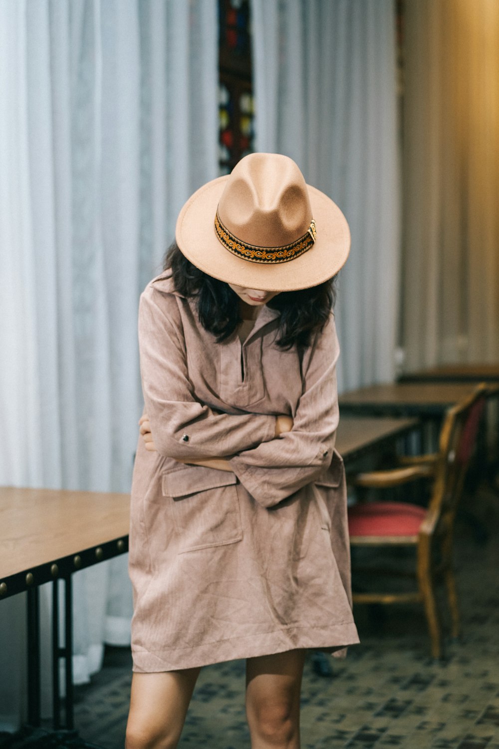 a woman wearing a hat standing in front of a table