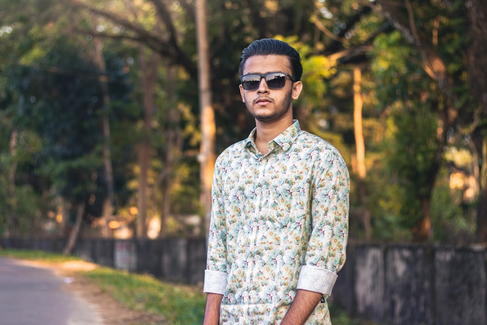 a man standing on the side of a road wearing sunglasses