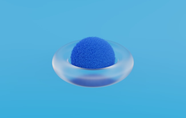 a blue sponge in a glass bowl on a blue background