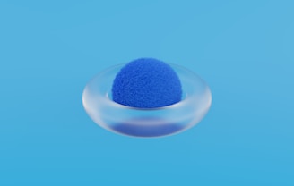 a blue sponge in a glass bowl on a blue background