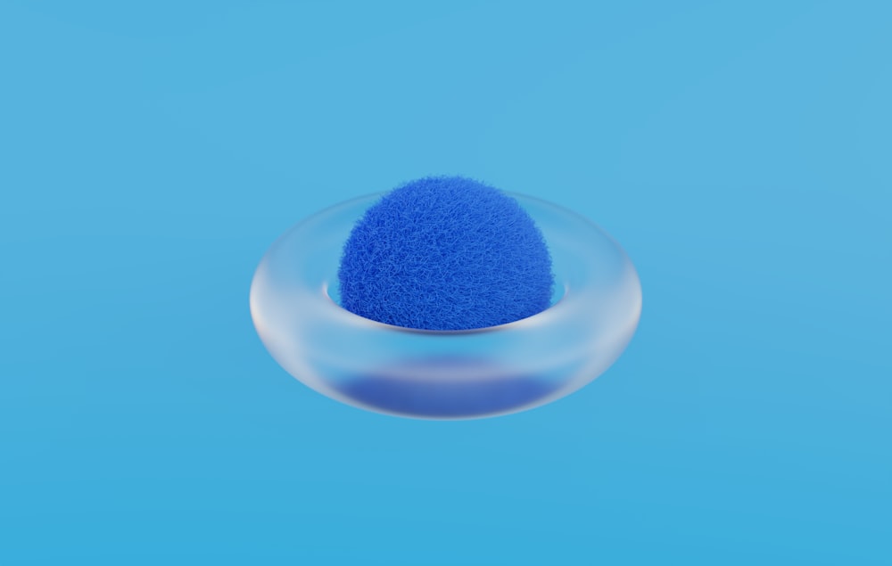 uma esponja azul em uma tigela de vidro em um fundo azul