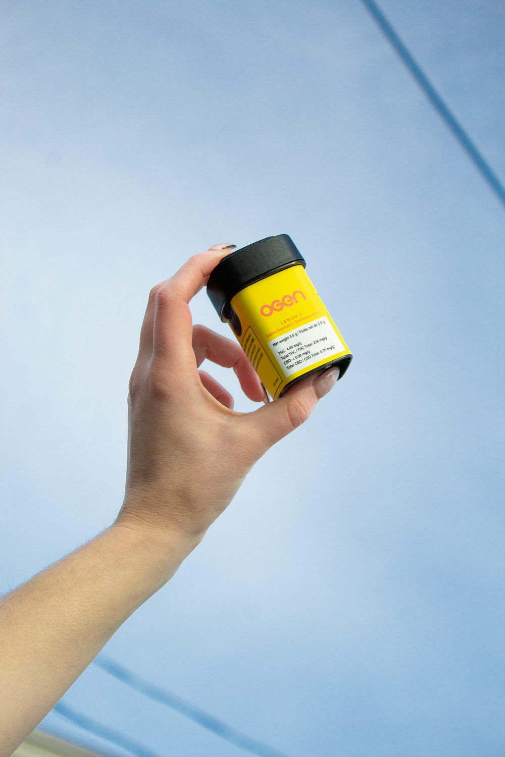 a hand holding a yellow and black container