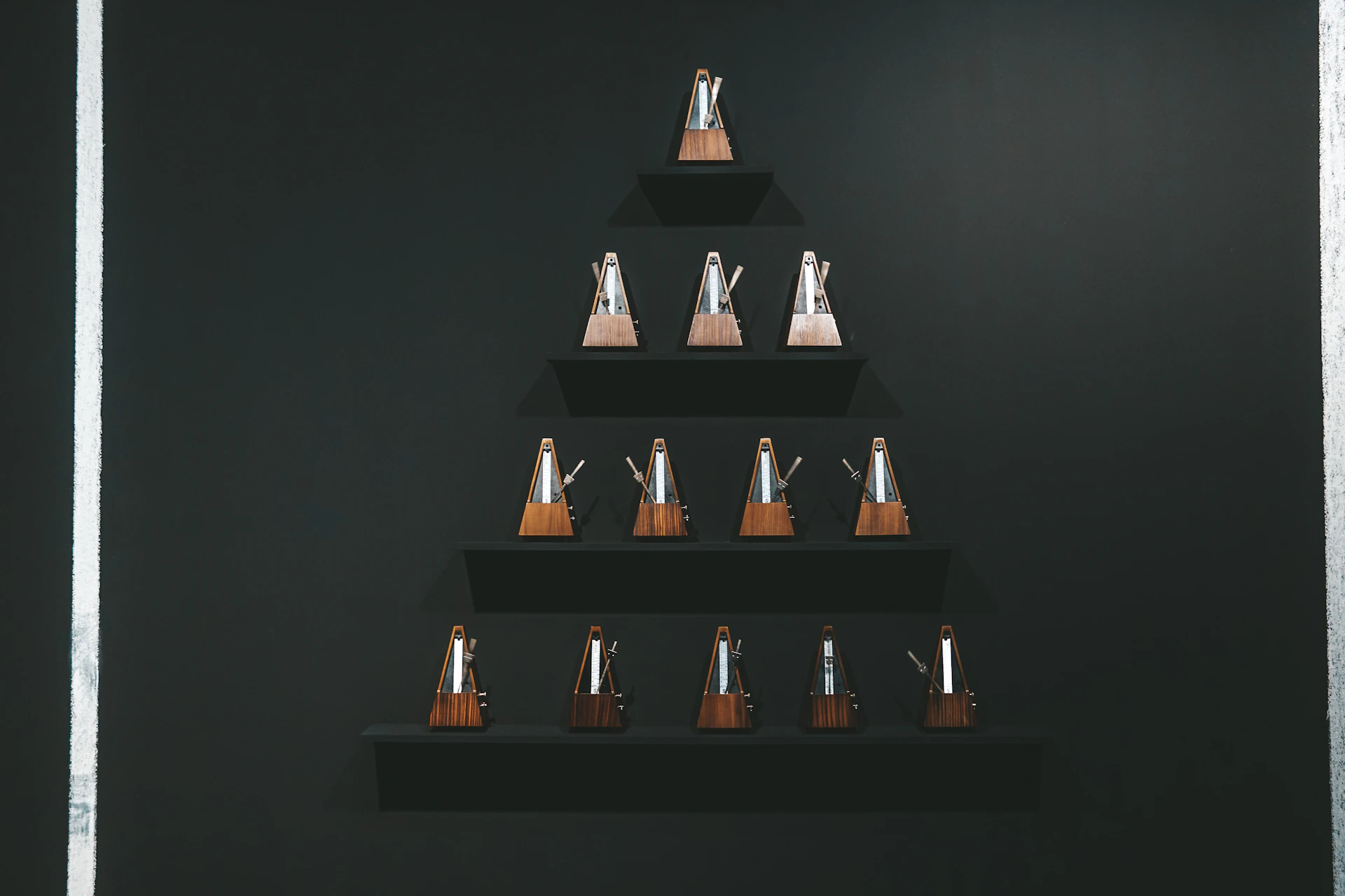 a black wall with a wooden shelf with a christmas tree on it