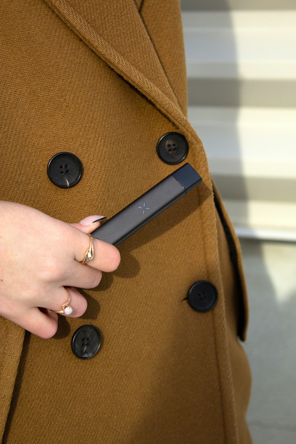 a woman in a trench coat holding a cell phone