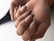 A close-up view of hands displaying elegantly manicured nails with a glossy finish and green marble tips. The skin tone is warm, and the lighting is soft, creating a gentle and sophisticated impression.