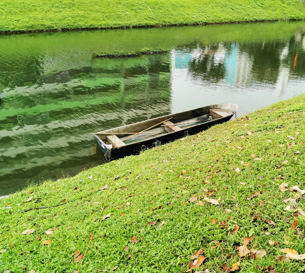 a small boat sitting on top of a lush green field