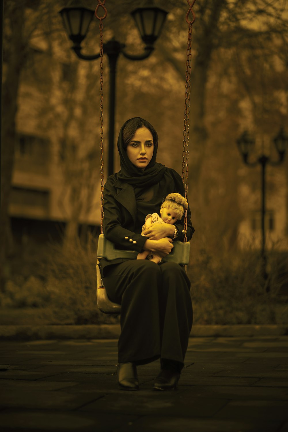 a woman sitting on a swing holding a baby
