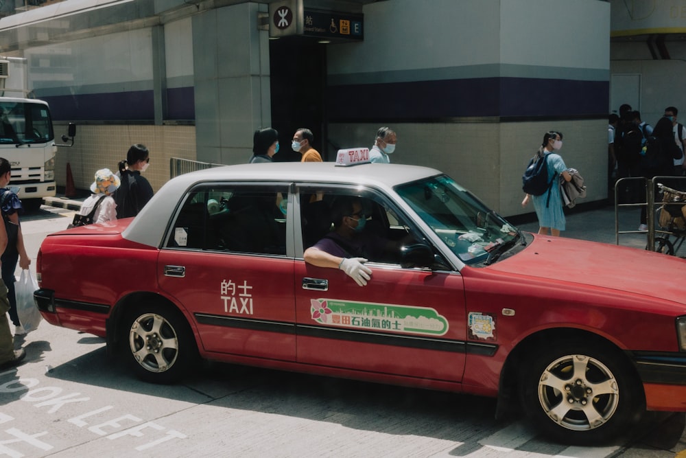 a red taxi cab with a man sitting in the driver's seat