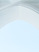 A minimalist architectural design featuring a smooth, arched ceiling with clean lines. The surface is predominantly white, creating a serene and airy atmosphere.
