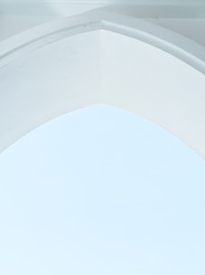 A minimalist architectural design featuring a smooth, arched ceiling with clean lines. The surface is predominantly white, creating a serene and airy atmosphere.