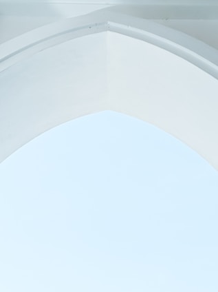 A minimalist architectural design featuring a smooth, arched ceiling with clean lines. The surface is predominantly white, creating a serene and airy atmosphere.