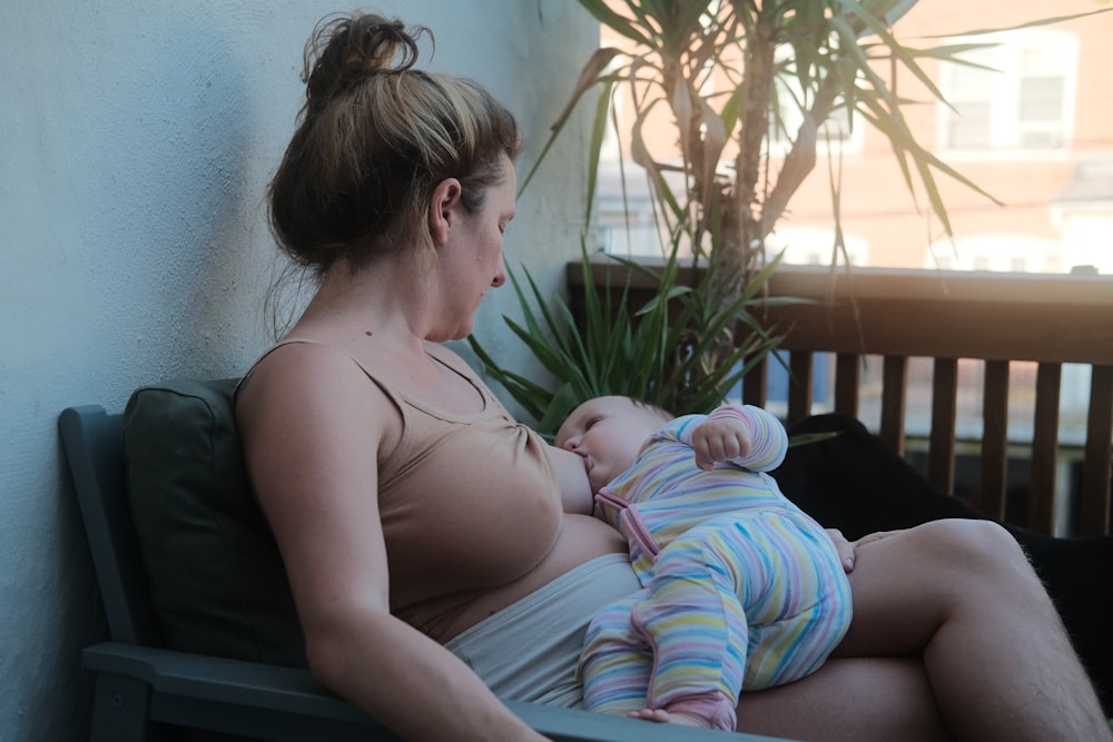 uma mulher sentada em um banco segurando um bebê