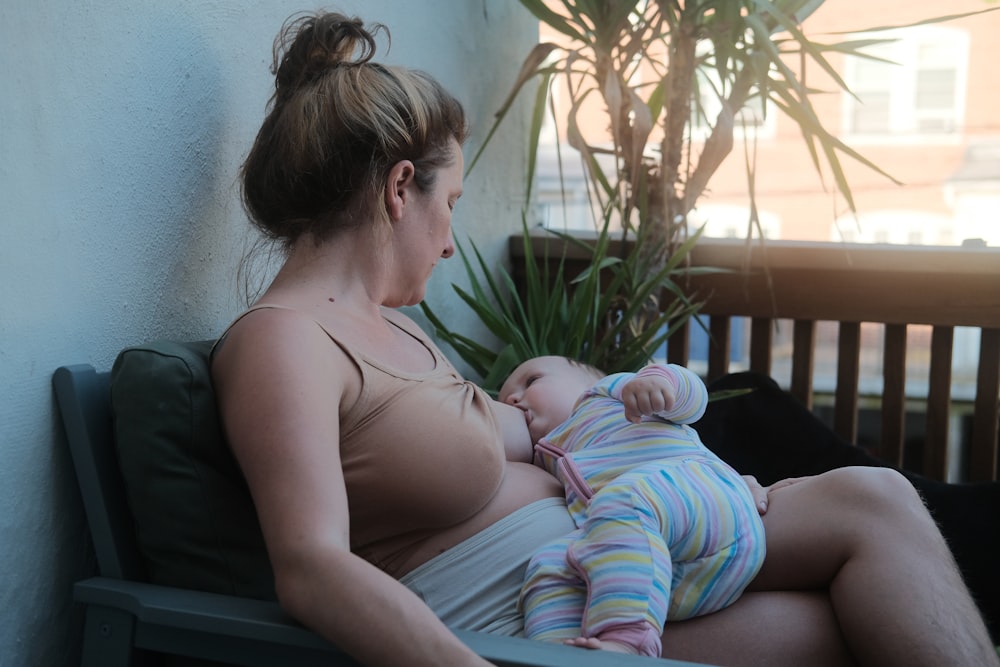 a woman sitting on a bench holding a baby