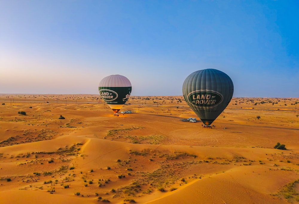 a couple of hot air balloons flying over a desert