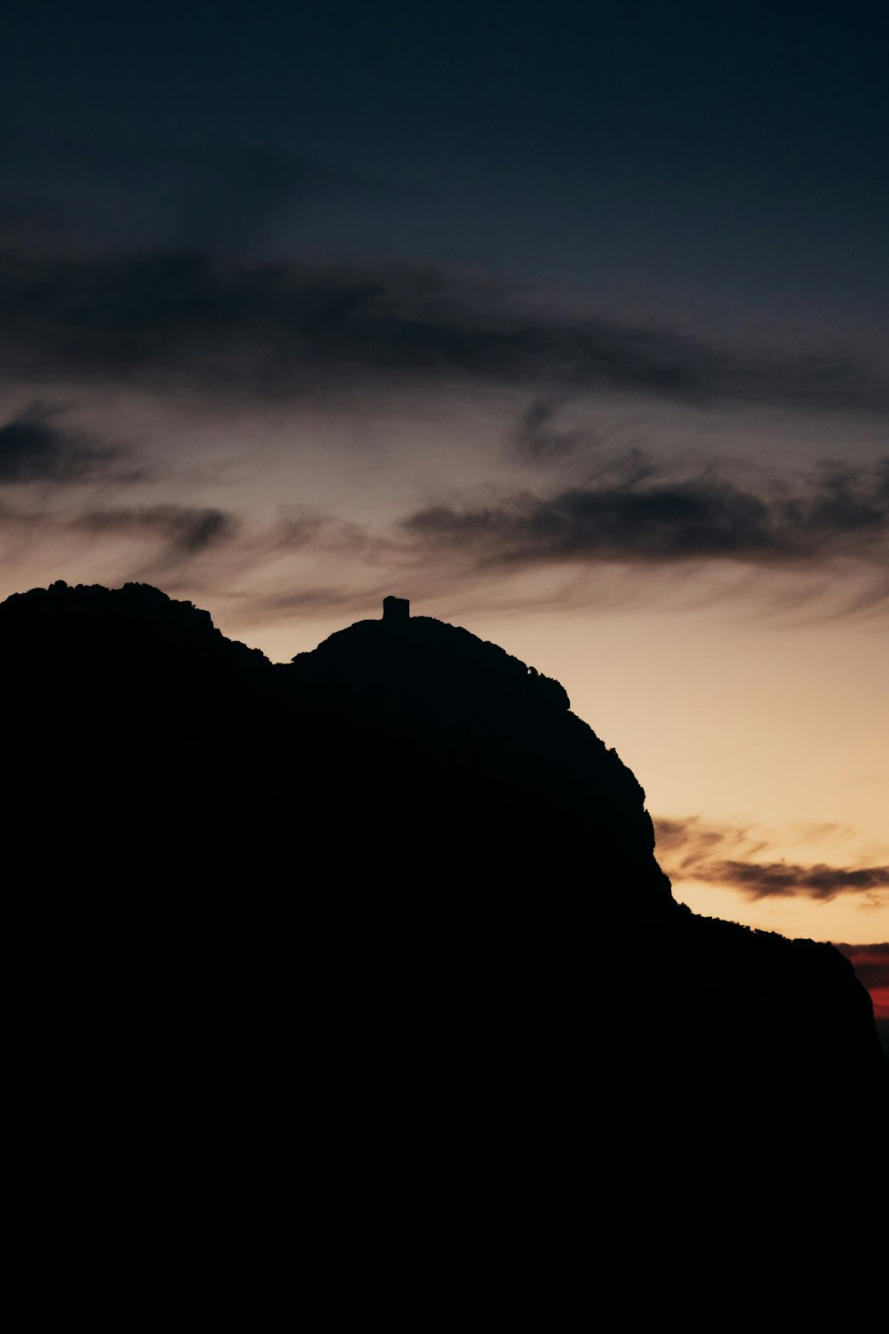 the silhouette of a mountain against a sunset