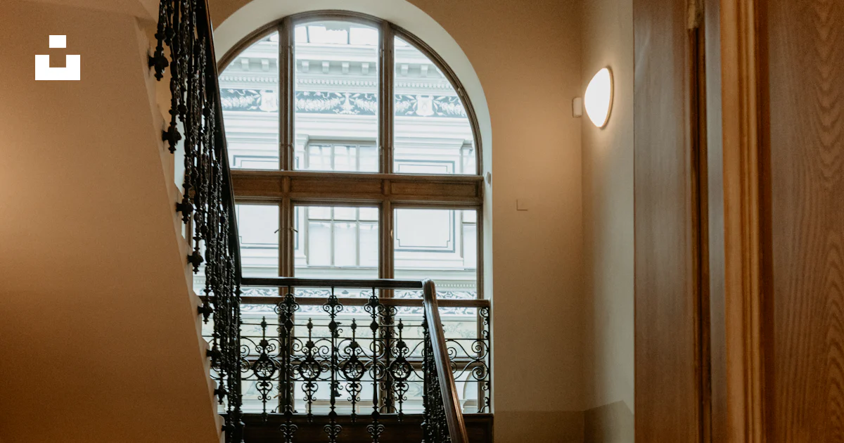 A staircase leading to a large window in a building photo – Free ...