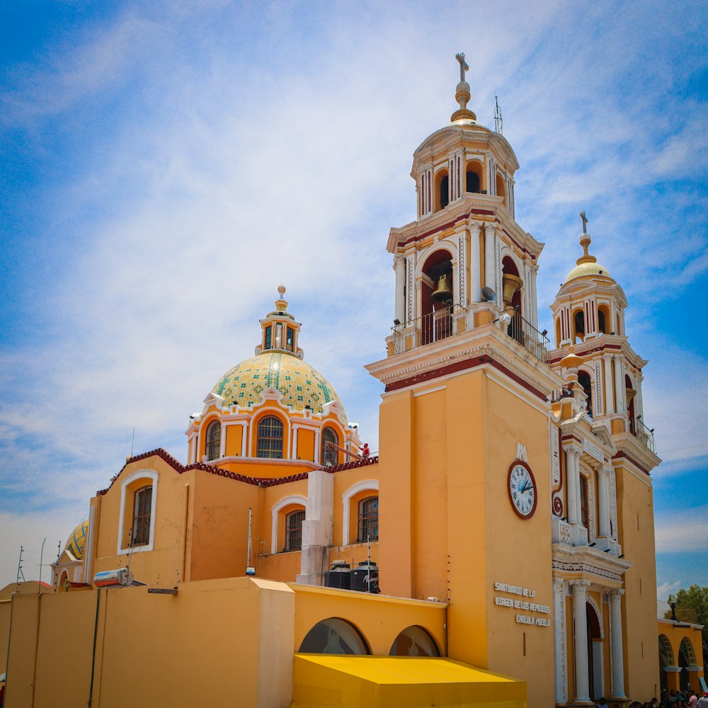 a large yellow building with a clock on it's side