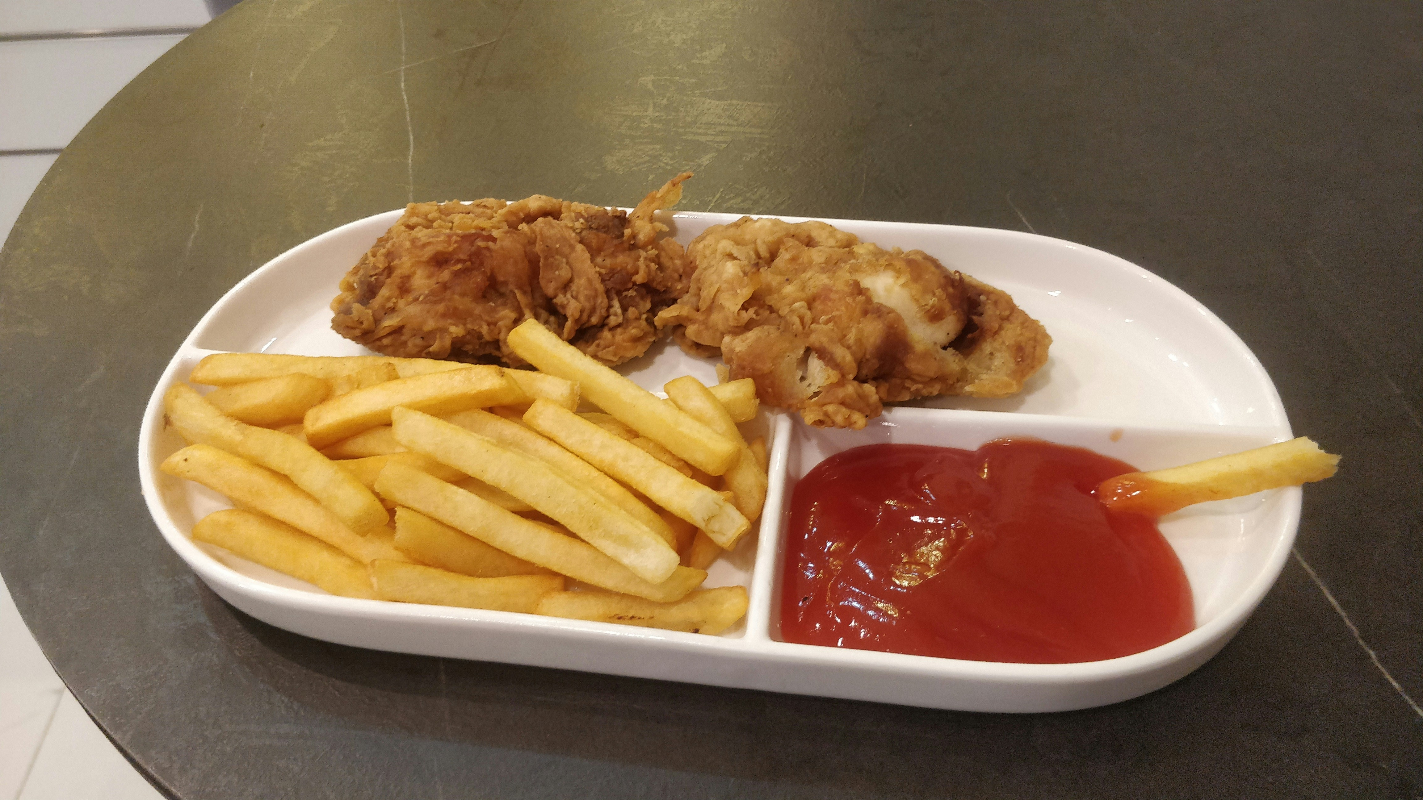 Golden fried chicken pieces on a white plate with lemon wedges