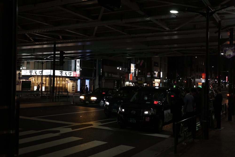 a busy city street at night with cars parked on the side of the road