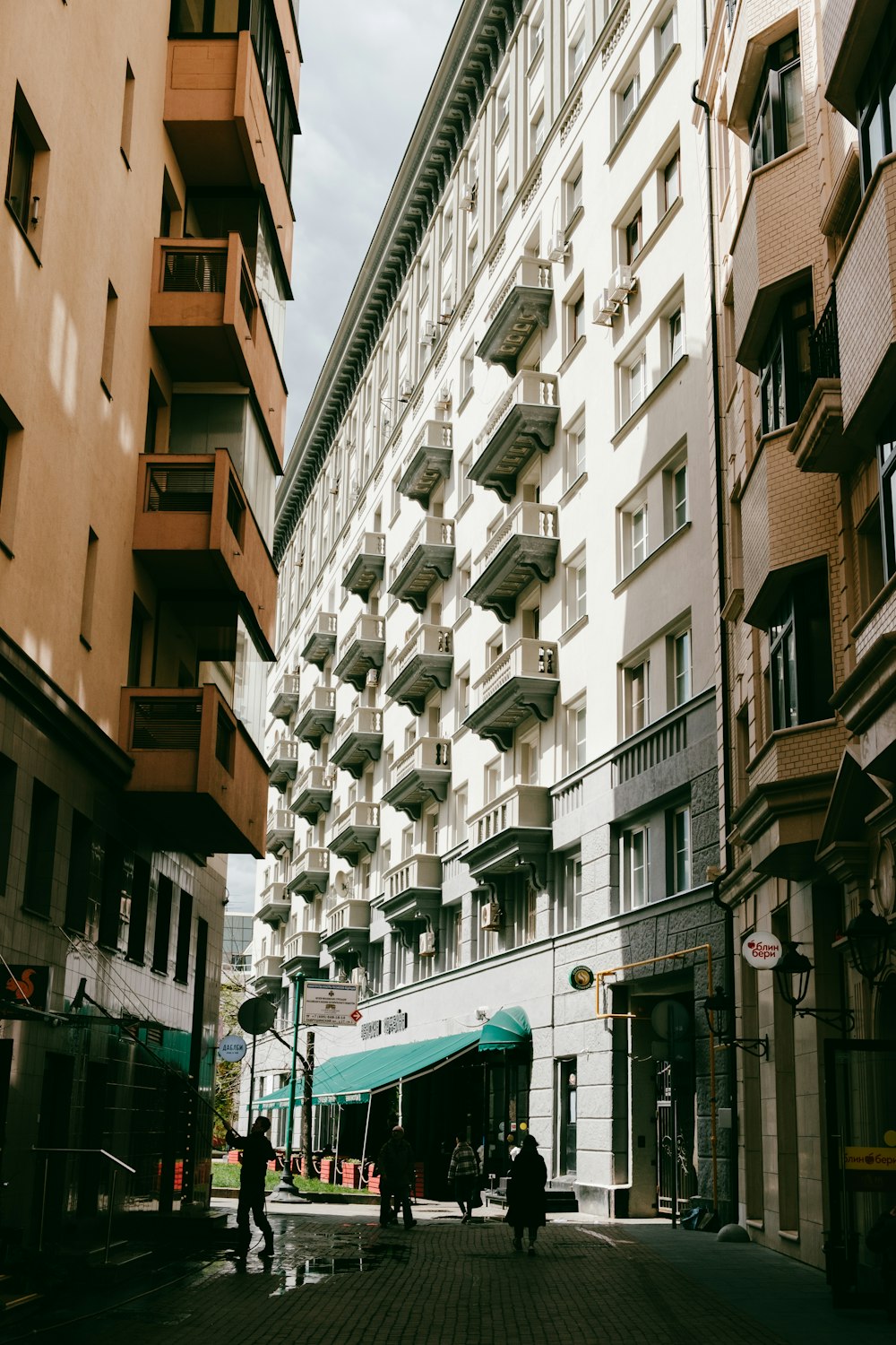 a group of people walking down a street next to tall buildings