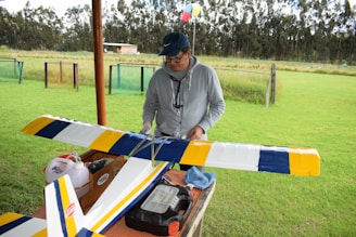 a man standing next to a yellow and blue airplane