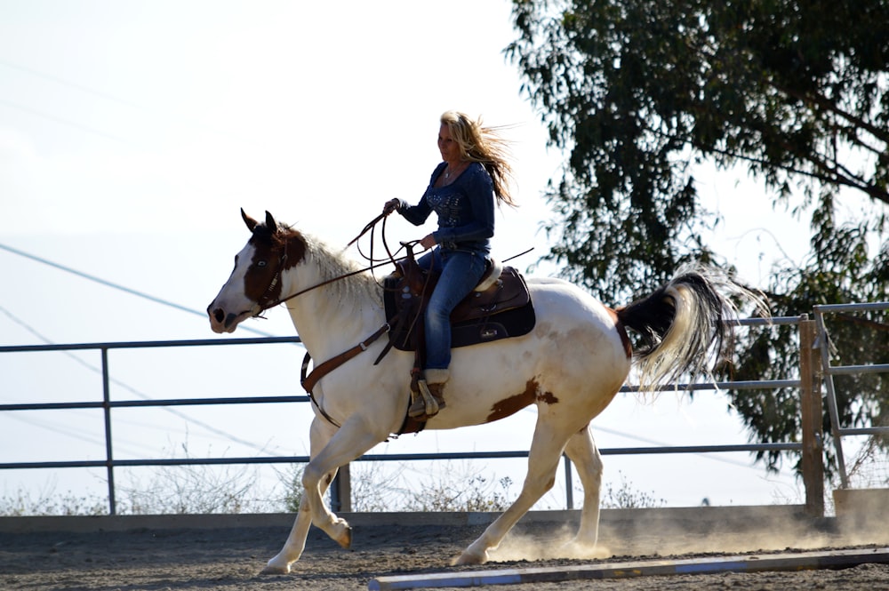 a woman riding on the back of a white horse