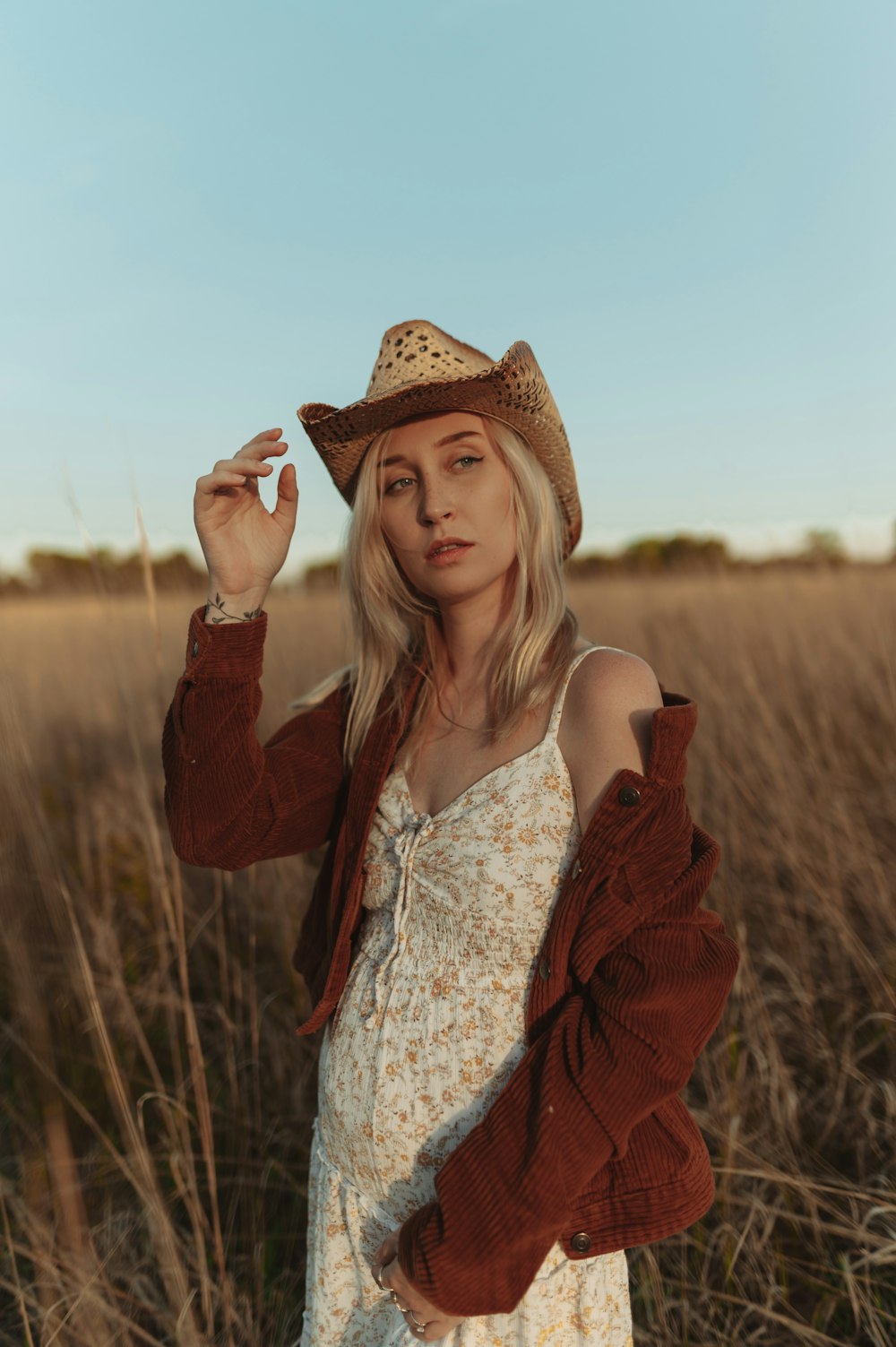 a woman standing in a field wearing a hat