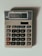 A beige calculator with multiple buttons, featuring a display that shows the number 3.14. The calculator has a solar panel and various function keys, including numerical digits, mathematical operations, and memory functions.