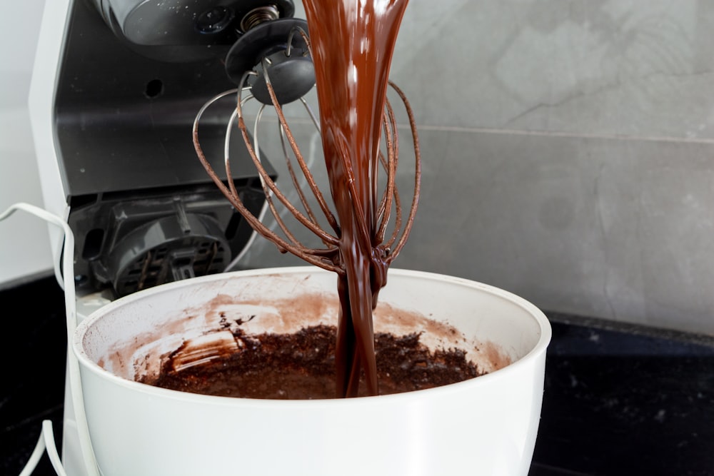 a chocolate cake being poured into a white bowl