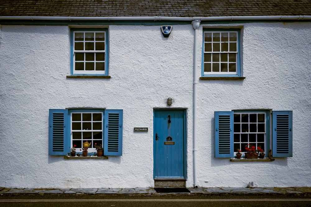 a white house with blue shutters and a blue door