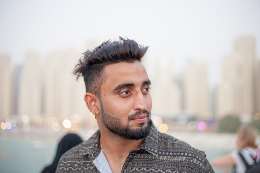 a man with a mohawk standing in front of a body of water