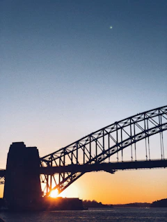 Sunset casting warm light over the Sumaré Bridge with a rapel participant nearing the bottom.
