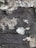 Peeling paint and rough texture of an old wall with uneven surface and patches of darker and lighter shades.