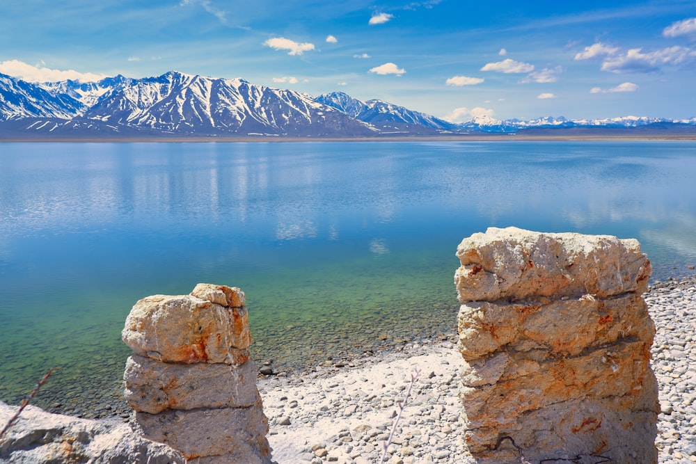 a lake with mountains in the background and rocks in the foreground