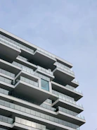 Modern residential building exterior with clean lines and glass balconies under a clear sky.