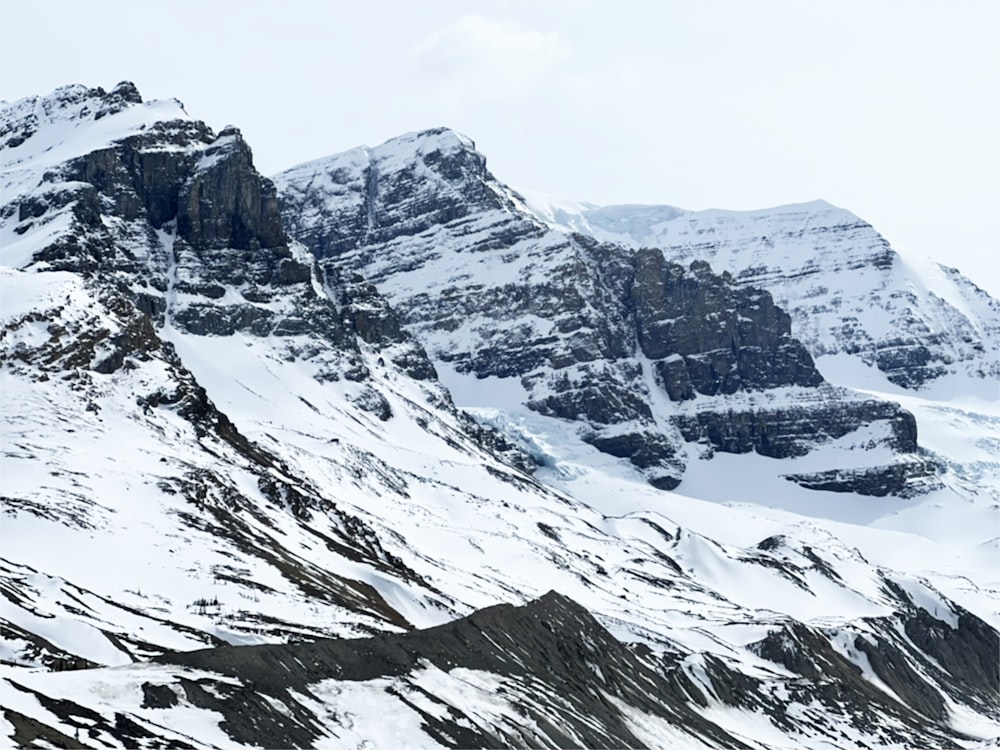 a snow covered mountain with a snowboarder in the foreground