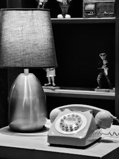 a lamp sitting on top of a table next to a phone
