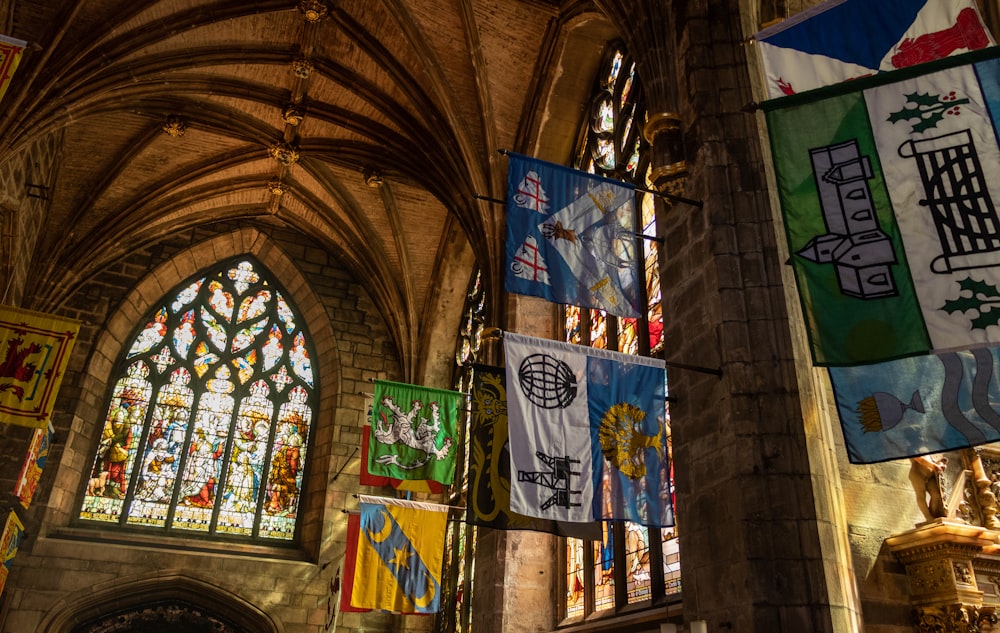 a cathedral with stained glass windows and banners hanging from the ceiling