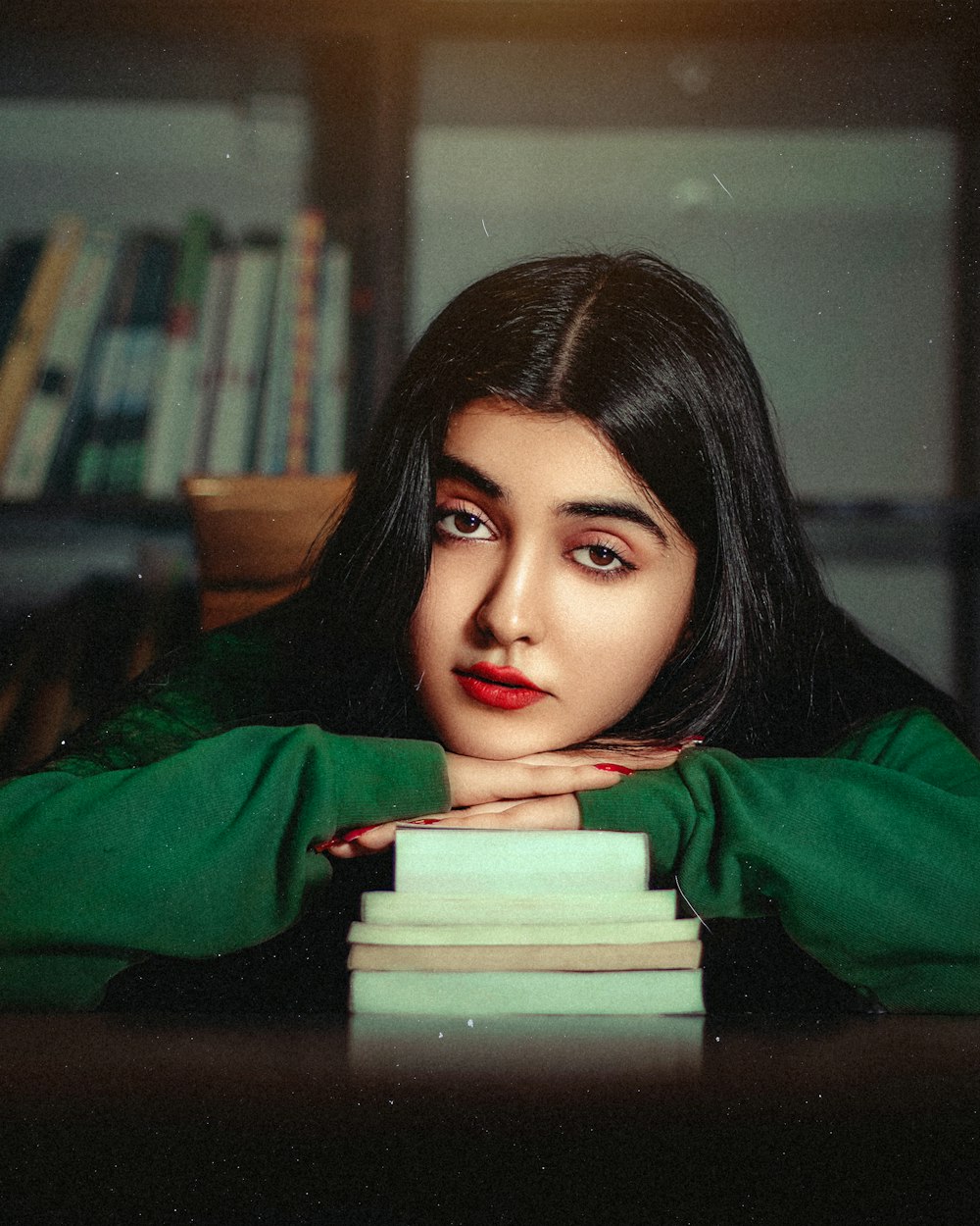 a woman leaning her head on a stack of books